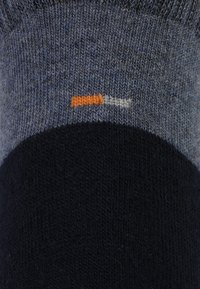 Calcetines de punto con una combinación de colores azul y marino. Patrón texturizado en el puño con un acento en naranja y blanco cerca de la parte inferior.