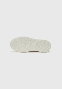 Sola di scarpa con motivo testurizzato e ondulato. Materiale in gomma prevalentemente bianco, con scanalature per trazione e stabilità.