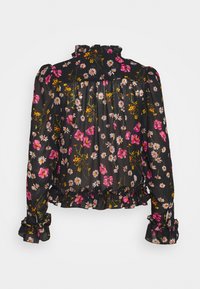 Blouse noire à fleurs avec manches longues ; motifs de fleurs roses et blanches, encolure et poignets à volants, corsage froncé, et tissu transparent.