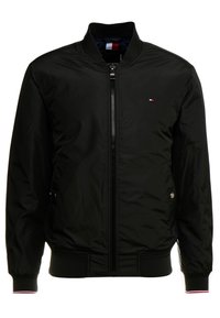 Sort bomberjakke med en frontlynlås, ribbede manchetter og et lille logo på den øverste venstre bryst. Glat, letvægtsstof.