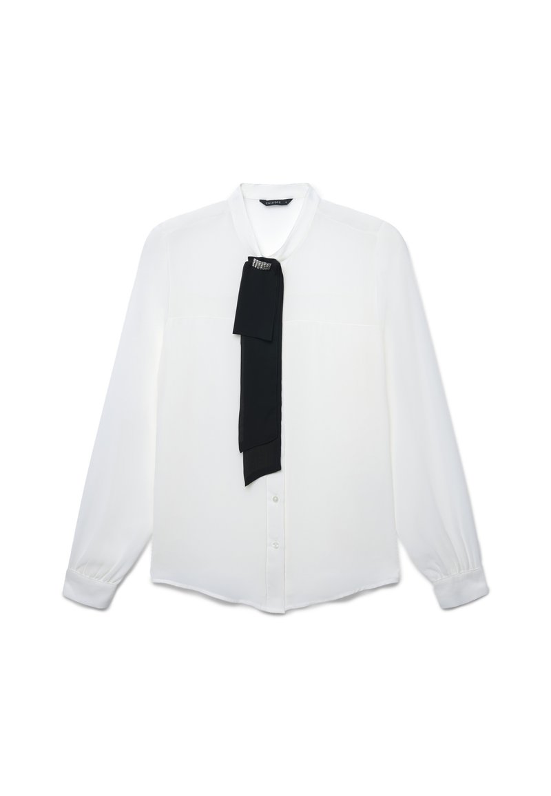 Blusa bianca a maniche lunghe con bottone frontale e una sciarpa decorativa nera appuntata vicino al colletto.