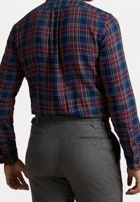 Koszula w kratę w kolorze niebieskim, czerwonym i żółtym, z długimi rękawami; szare spodnie z kieszeniami bocznymi i detalami z guzikami; teksturowany materiał.