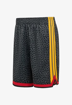Pantalones cortos deportivos negros con manchas de leopardo grises, franjas laterales amarillas y ribete rojo y negro en el dobladillo.