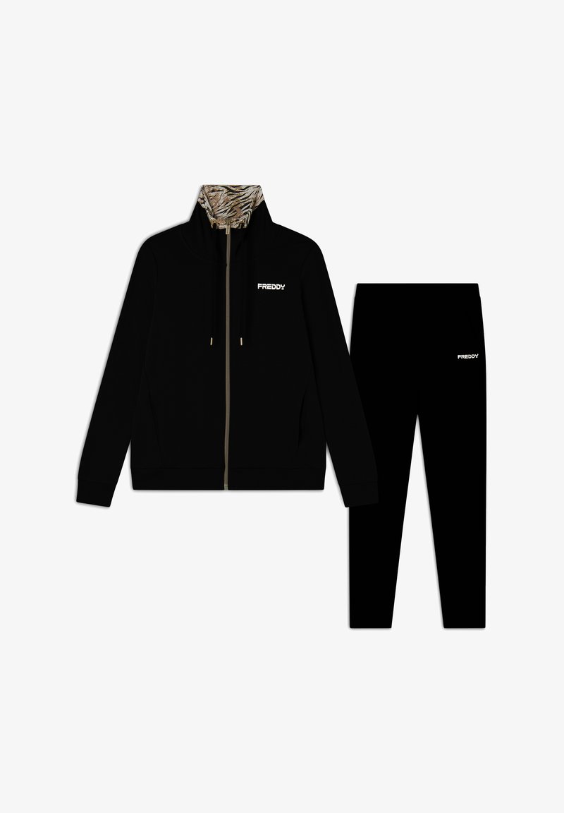 Chaqueta negra con cremallera y cuello de estampado de tigre, acompañada de pantalones negros a juego. Ambos presentan el logo "FREDDY" en blanco. Textura de tela suave.
