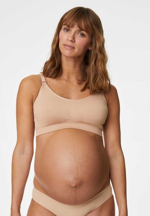 Sostén de maternidad beige con una textura suave y elástica, que presenta tirantes ajustables y un diseño sin costuras para mayor comodidad y soporte.