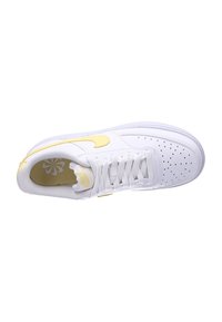 Sneaker bianca con accenti gialli, caratterizzata da una tomaia in pelle testurizzata, punta perforata e lacci piatti. Design low-top con collare imbottito.