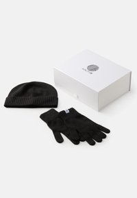 Gorro de malha preto com uma fita canelada e luvas combinando com uma etiqueta, expostos com uma caixa branca com um logo.