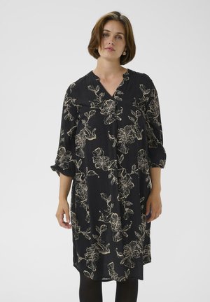 Schwarzes Kleid mit floralen Muster in Beige. V-Ausschnitt, Dreiviertelärmel und lockere Passform. Hergestellt aus leichtem Stoff mit weicher Textur.