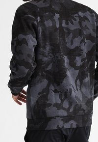 Felpa nera e grigia con un motivo camouflage testurizzato, collo rotondo, maniche lunghe e orlo a coste.