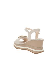 Sandalo con zeppa in tessuto beige con cinturini incrociati, punta aperta, accentuazione verticale del tacco e suola a strati bianca e marrone per un supporto aggiuntivo.