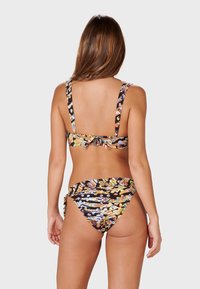 Bikini med ett flerfärgat abstrakt mönster, med bredare remmar, justerbar ryggknut och en låg midja med sidoknutar.