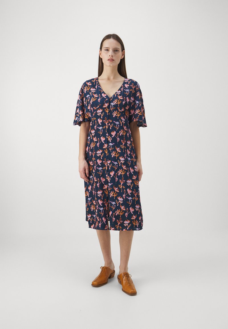 Marinblå klänning med blommönster i rosa och orange nyanser, korta fladdrande ärmar, V-ringning, knälång, lätt knappdetalj fram.