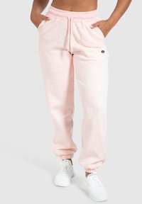 Lichtroze sweatpants gemaakt van zachte stof, met een koord in de taille, zijzakken en elastische boorden bij de enkels.