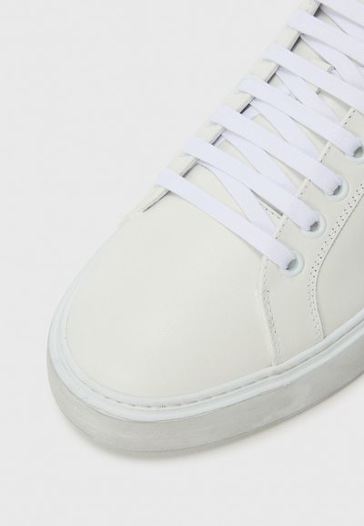 Sneaker bianco in pelle con punta arrotondata, chiusura con lacci e suola in gomma. Presenta dettagli di cucitura discreti e passanti per i lacci.