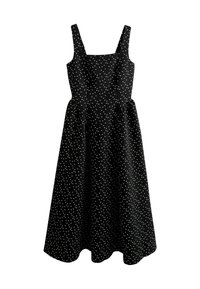 Black cotton dress with white polka dots, square neckline, and adjustable straps. Flared silhouette with a mid-length hemline.