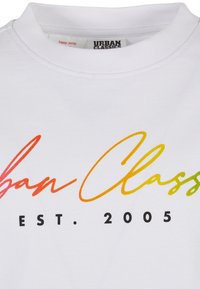 Bílý bavlněný tričko s barevným gradientním textem "Urban Classics EST. 2005" ve kurzívě. Jednoduchý design s kulatým výstřihem.