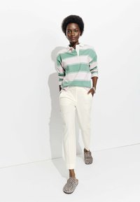 Polo à manches longues rayé vert et rose, pantalon crème et chaussures à enfiler imprimé léopard. Tissu lisse et coupe décontractée.