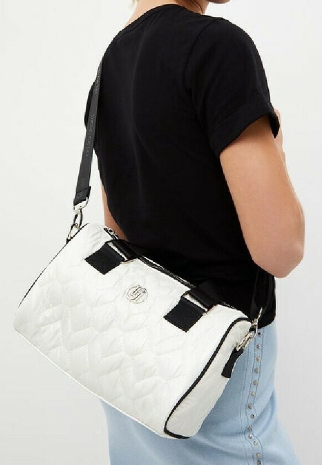 Personne portant une chemise noire et un jean bleu clair avec un sac à main matelassé blanc avec des bretelles noires et des ferrures argentées sur l'épaule.