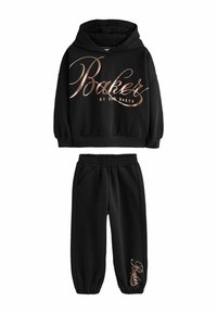Černá mikina s lesklou růžovou zlatou grafikou "Baker" v kombinaci s odpovídajícími černými tepláky, které mají akcentované logo na lemu.