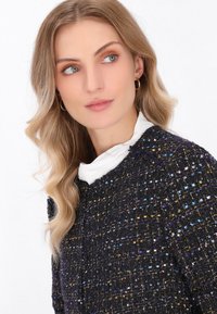 Maglione a maglia nero e viola con dettagli in filo colorato, scollatura rotonda e colletto bianco a strati. Leggero luccichio.