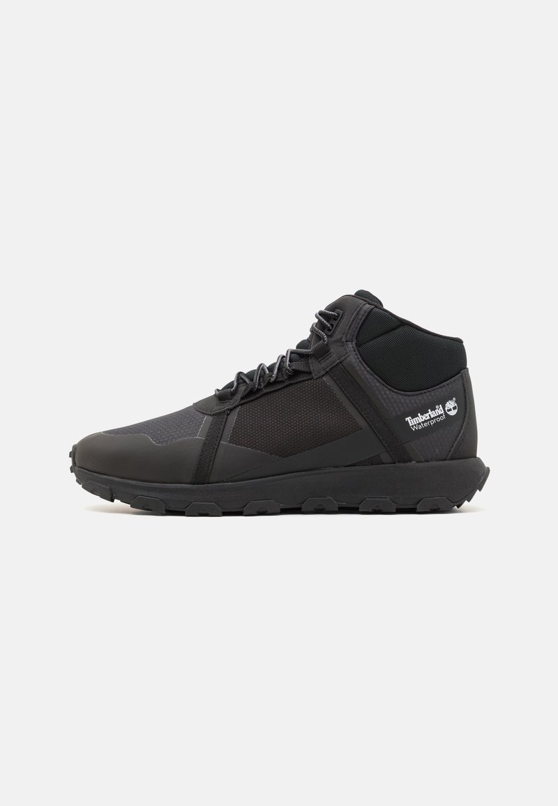 Schwarze Mid-Height Sneakers mit einer Mischung aus glatten und Mesh-Oberflächen. Merkmale sind eine Gummisohle, verstärkte Ferse und das Timberland-Logo an der Seite.