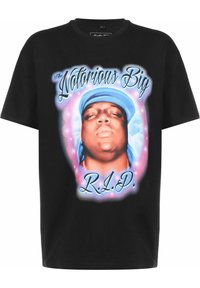 Melna T-krekls, izgatavots no kokvilnas, ar lielu grafisku attēlu, kurā attēlots vīrieša seja, ko ieskauj krāsains halo un teksts "The Notorious Big R.I.P."