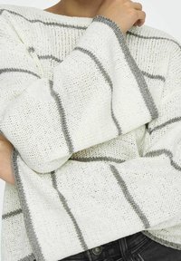 Dzianinowy sweter w kolorze ecru z szarymi, poziomymi paskami. Posiada szerokie, dzwonowate rękawy oraz teksturowaną tkaninę o luźnym kroju.