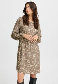 Blumenmuster-Kleid in Hellbraun, mit rundem Ausschnitt und Puffärmeln. Der Stoff hat eine weiche Textur; knieumspielende Länge.