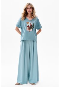 T-shirt léger bleu clair à manches amples avec un col en V et un imprimé graphique, associé à un pantalon large bleu clair, présentant une texture lisse.