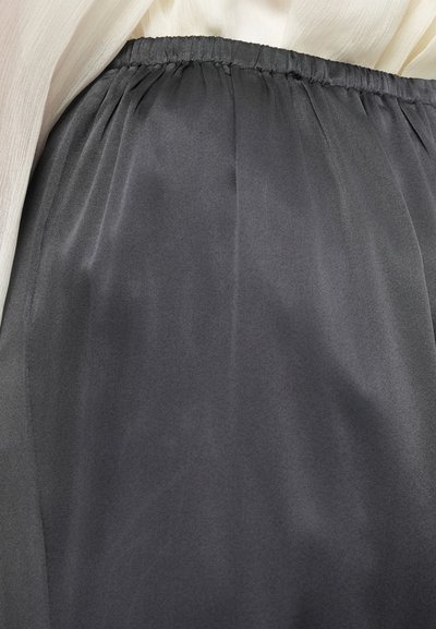 Jupe légère grise avec une ceinture élastique, présentant une texture lisse et un tissu fluide qui tombe délicatement.