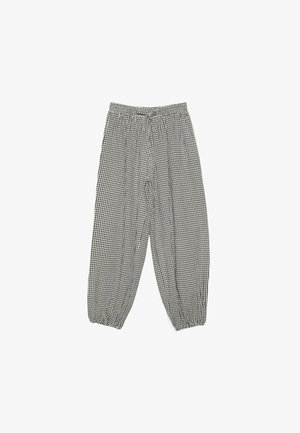 Pantaloni neri e bianchi a quadretti a vestibilità ampia con vita elastica e polsini elastici, distesi su uno sfondo bianco.