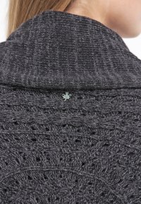 Dunkelgrau gestrickter Pullover mit einem strukturierten Design, ausgestattet mit einem Kragen und einem kleinen dekorativen Etikett in der Nähe des Halsausschnitts.