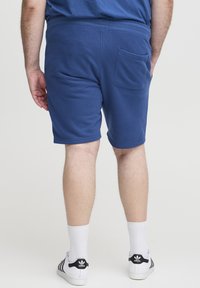 Blå bomuldsshorts med tekstureret finish, en baglomme og en afslappet pasform, stylet med hvide sokker og sneakers med sorte striber.
