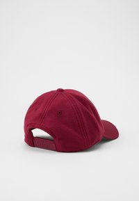 Bordeauxkleurige fleece pet met een gebogen klep, voorzien van een plastic verstelbare band aan de achterkant met de opdruk "HUGO" en stikseldetails.