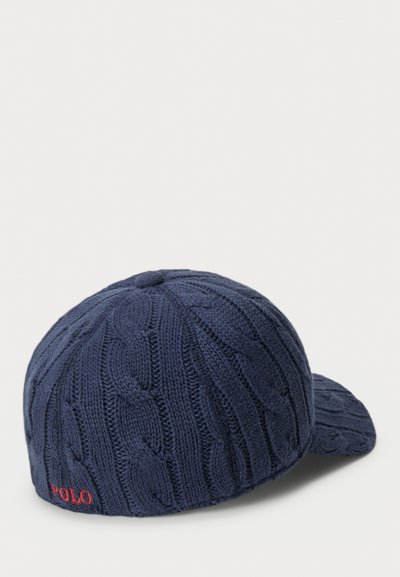 Navy knit cap with cable pattern, structured shape, and curved brim. Features red "POLO" logo on the side. Textured fabric for warmth.