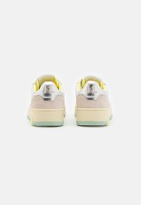 Sneakers z miękką szaro-białą cholewką, metalicznymi akcentami, beżowym zamszowym obcasem i miętową podeszwą. Żółte detale widoczne wewnątrz.