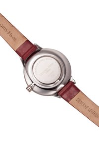 Fond de montre en acier inoxydable rond avec texte en relief. Bracelet en cuir véritable bordeaux avec sous-couche beige. Finition métallique polie.