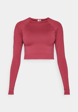 Ilgi piedurkņu saspiestais tops dziļi sarkanā krāsā, izgatavots no elastīga auduma. Ar apaļu izgriezumu un ribotu apakšmalu un piedurkņu galiem. Gluda tekstūra.