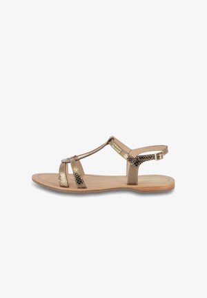 Sandales plates métallisées dorées avec plusieurs brides, une bride arrière à la cheville et une finition texturée. La semelle est tan avec une surface lisse.