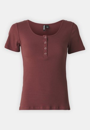 T-shirt bordeaux à côtes avec des manches courtes et décolleté en scoop, présentant un plastron avec quatre boutons métalliques.