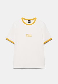 T-shirt blanc à manches courtes avec bordure jaune au col et aux manches, avec texte jaune « Art lives in the Streets » sur la poitrine.