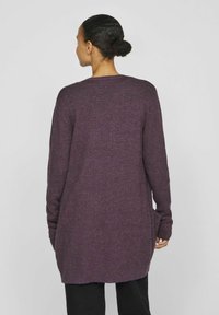 Lång, öppen cardigan i mörklila stickad tyg. Har långa ärmar och en avslappnad passform med sidoklipp för komfort. Inga synliga dekorationer.