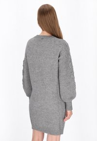 Grå strikket sweaterkjole med rund hals, teksturerede ballonærmer og ribbede manchetter, lavet i en blød, chunky garn.