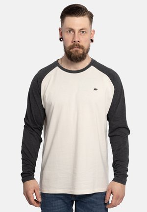 Langemouwige raglan shirt met een crème kleurige romp en donkergrijze mouwen. Opvallende berenafbeelding op de linkerkant van de borst. Zacht katoenmix stof.