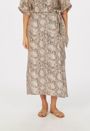 Lightweight, mid-length dress in beige with a snake print pattern. Features a tied waist and short rolled sleeves, paired with gold sandals.