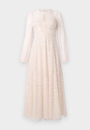 Lang gennemsigtig blush pink kjole med sølvfarvede pailletter, lange ærmer, en lille nøglehulsudskæring og en tætsiddende talje.