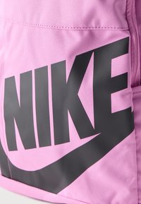 Ροζ υφασμάτινο σακίδιο πλάτης με μεγάλο μαύρο λογότυπο NIKE και σχεδιασμό κυματιστού σήματος στην μπροστινή τσέπη.