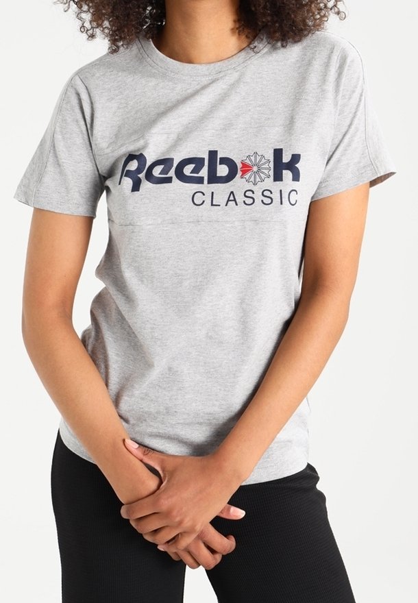 T-shirt en coton gris avec le logo "Reebok CLASSIC" en bleu marine, à manches courtes et encolure ronde. Texture douce, coupe décontractée.