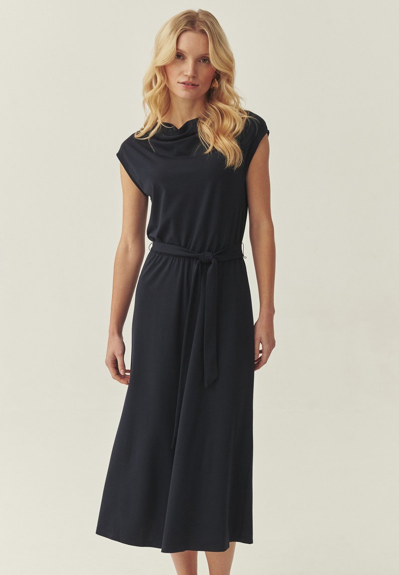 Robe midi bleu marine avec manches courtes, col bénitier et ceinture nouée à la taille. Tissu lisse avec bas fluide et design minimaliste.