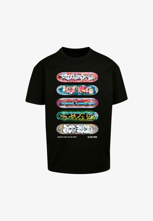 Black t-shirt featuring five skateboard decks with colorful graffiti designs. Text at the bottom reads "FROM THE STREET FOR THE STREET."